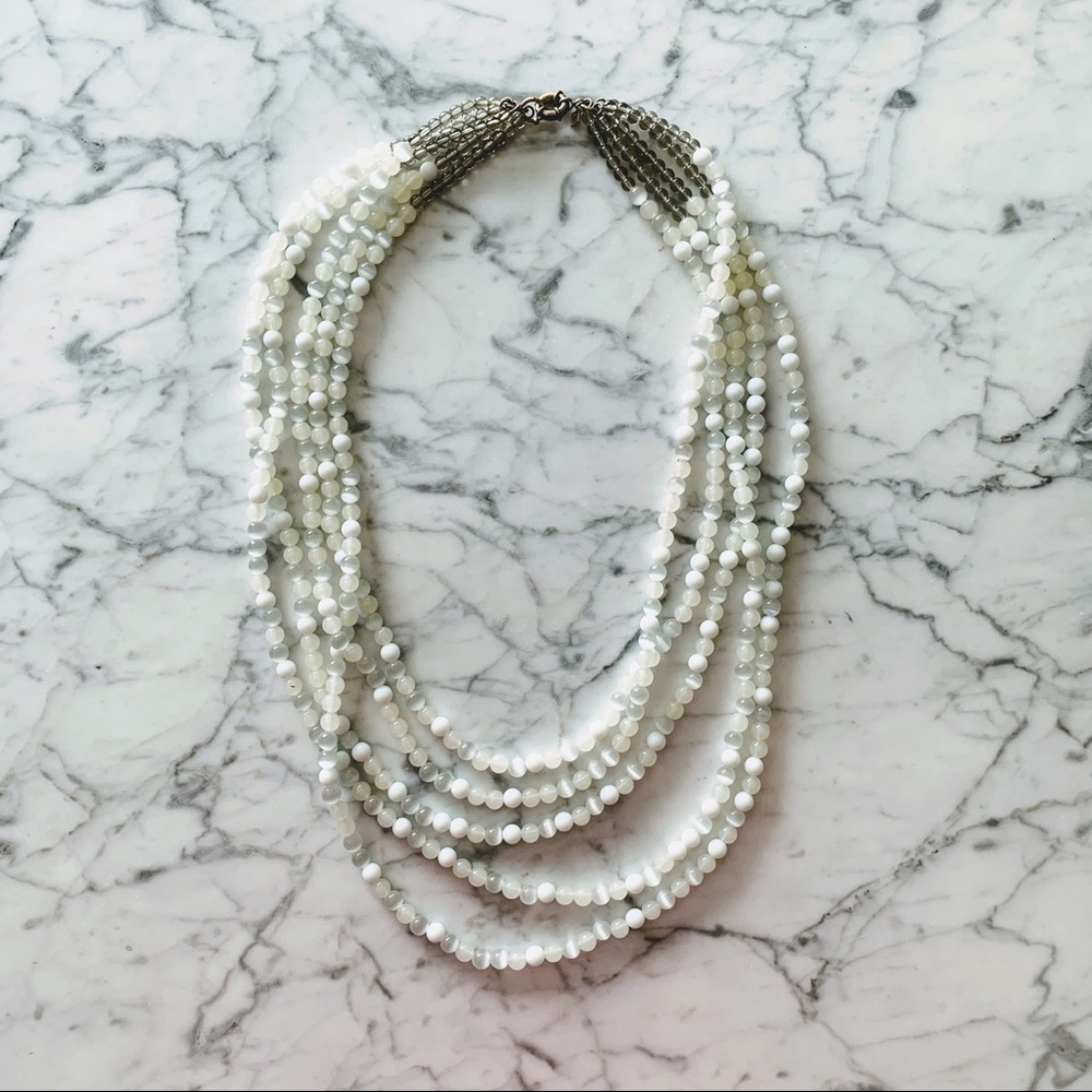 Long white multi-strand bead necklace.